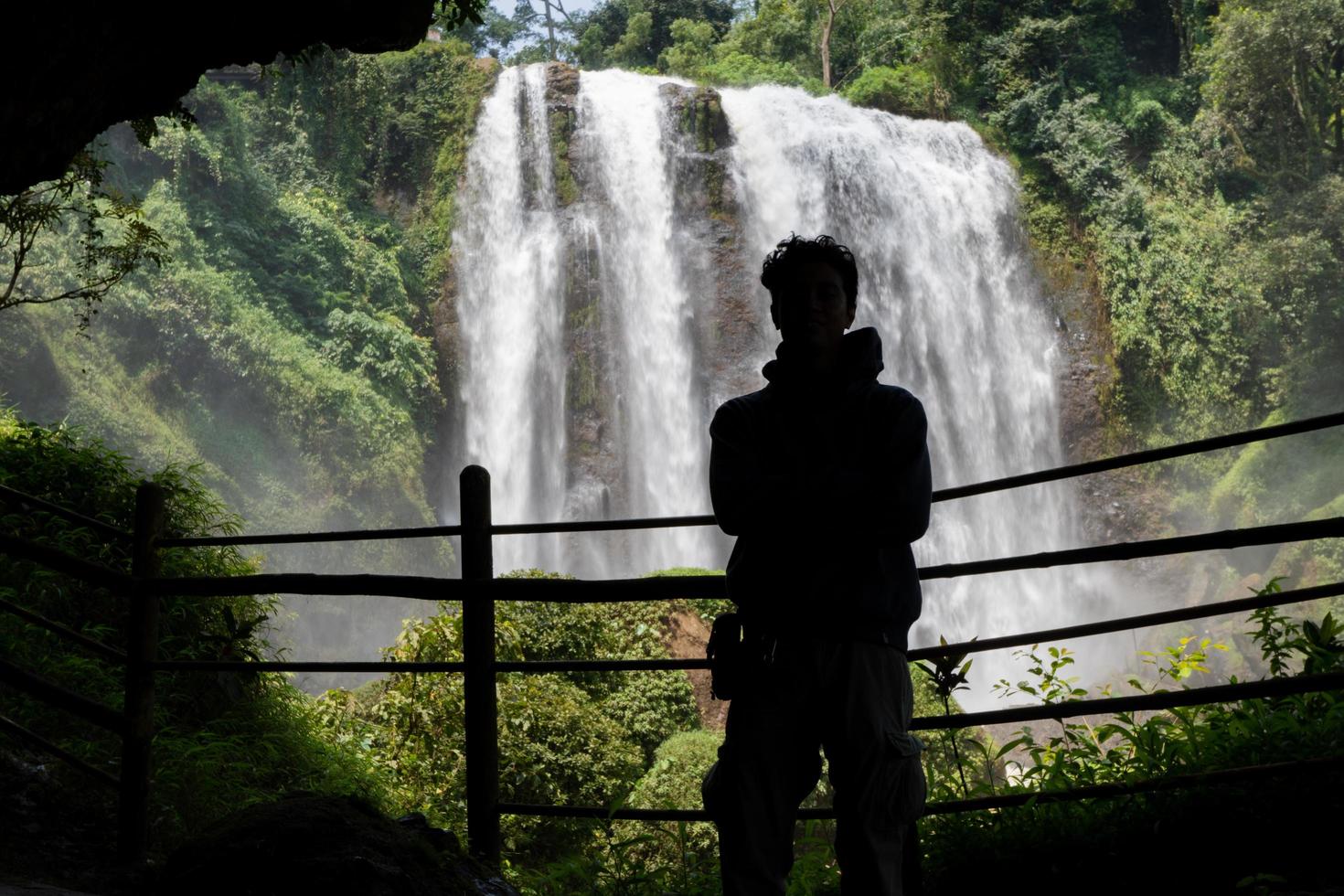 Silhouette man on the cave in front of great water fall, Semarang Central Java. The photo is suitable to use for adventure content media, nature poster and forest background.