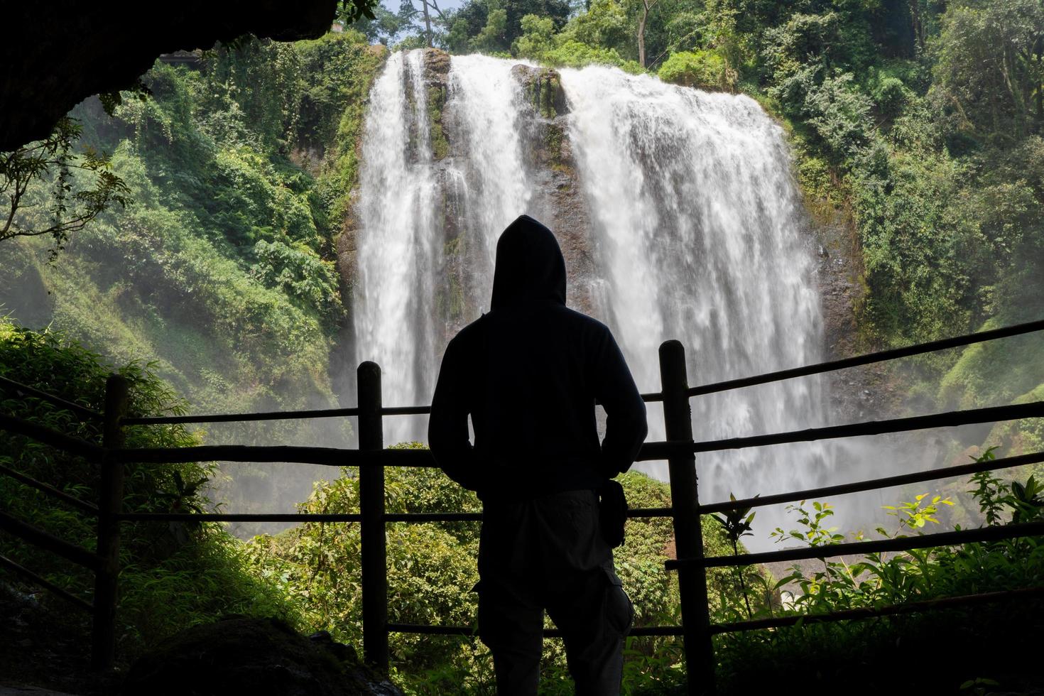 Silhouette man on the cave in front of great water fall, Semarang Central Java. The photo is suitable to use for adventure content media, nature poster and forest background.