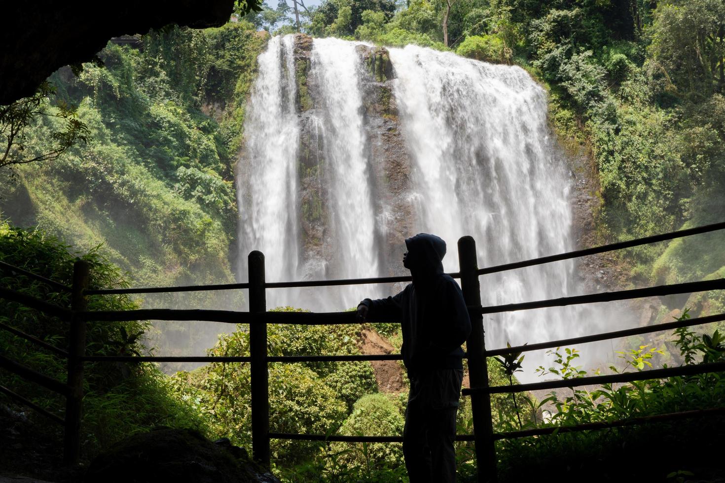 Silhouette man on the cave in front of great water fall, Semarang Central Java. The photo is suitable to use for adventure content media, nature poster and forest background.