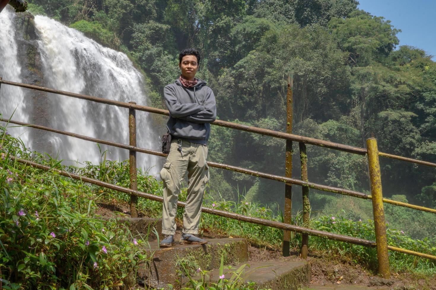 hombre estar vestir con capucha en frente de el genial agua otoño con mano carrete, semarang central Java. el foto es adecuado a utilizar para aventuras contenido medios de comunicación, naturaleza póster y bosque antecedentes.