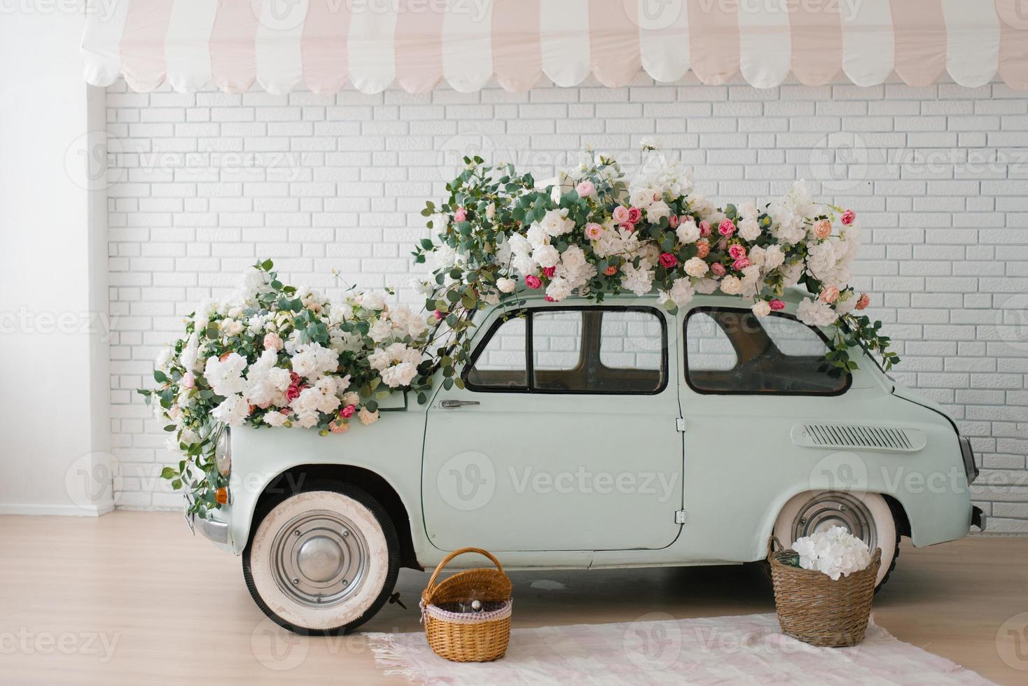 Retro mint car decorated with flowers in the photo zone in a romantic style for Spring Day or St. Valentine