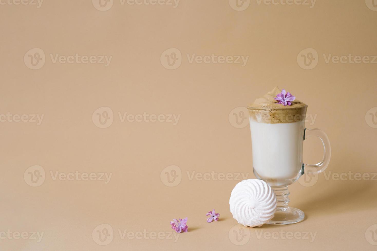 Beautiful dalgon coffee drink with foam in a transparent Cup and marshmallows on a beige background. Copy space photo