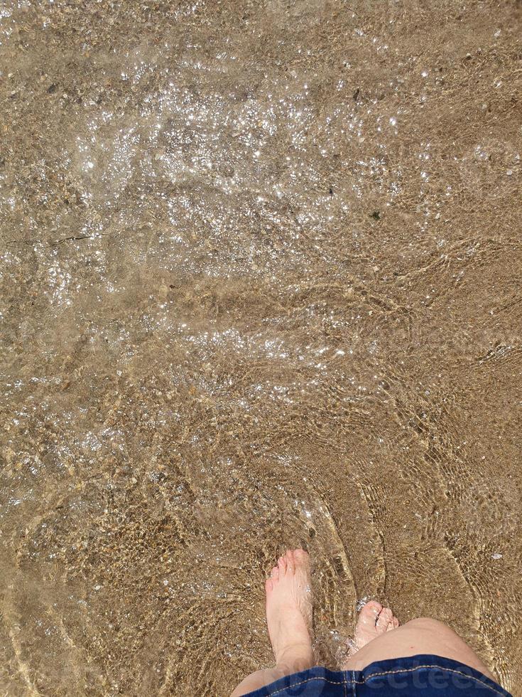 woman's  feet immersed in the sea water at the beach on a sunny warm day photo