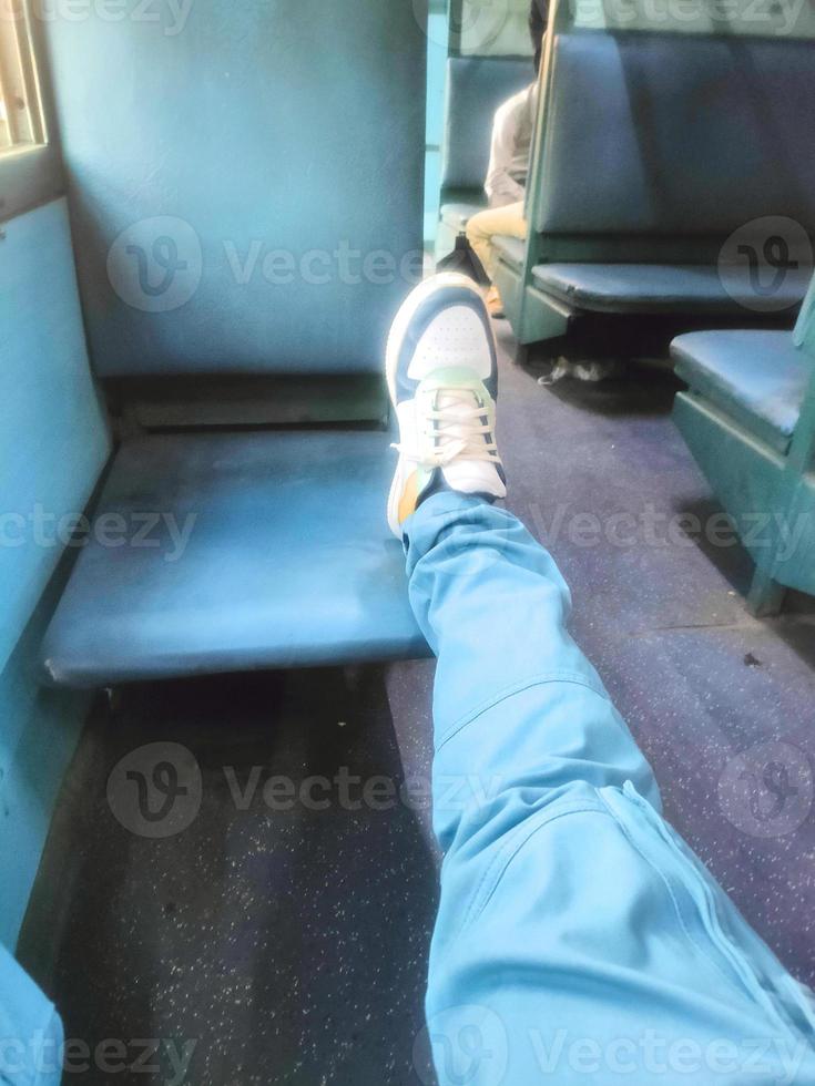 un grosero pasajero sentado en tren con uno pierna es en otro asiento foto