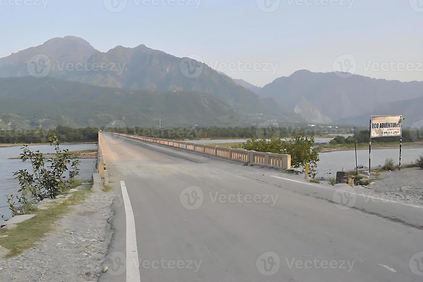 A narrow bridge road on Sindhu River in Kashmir with warning sign photo