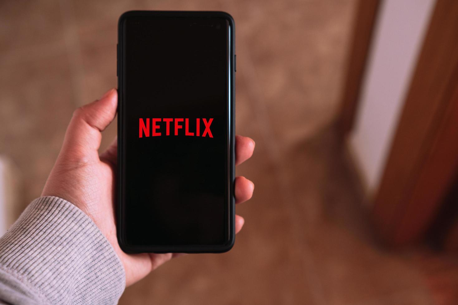 MALAGA, SPAIN, APRIL 6, 2023, Woman streaming Netflix on smartphone. Digital devices. App mobile. Netflix and chill. photo