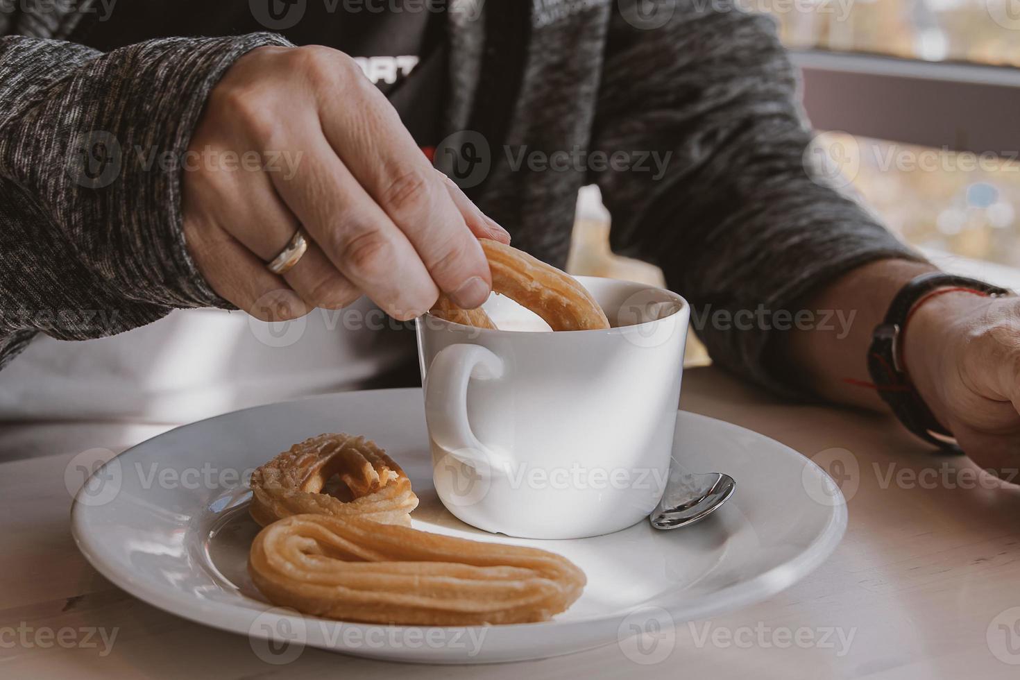 close-up of a man eating a typical  Spanish breakfast and churros with chocolate photo