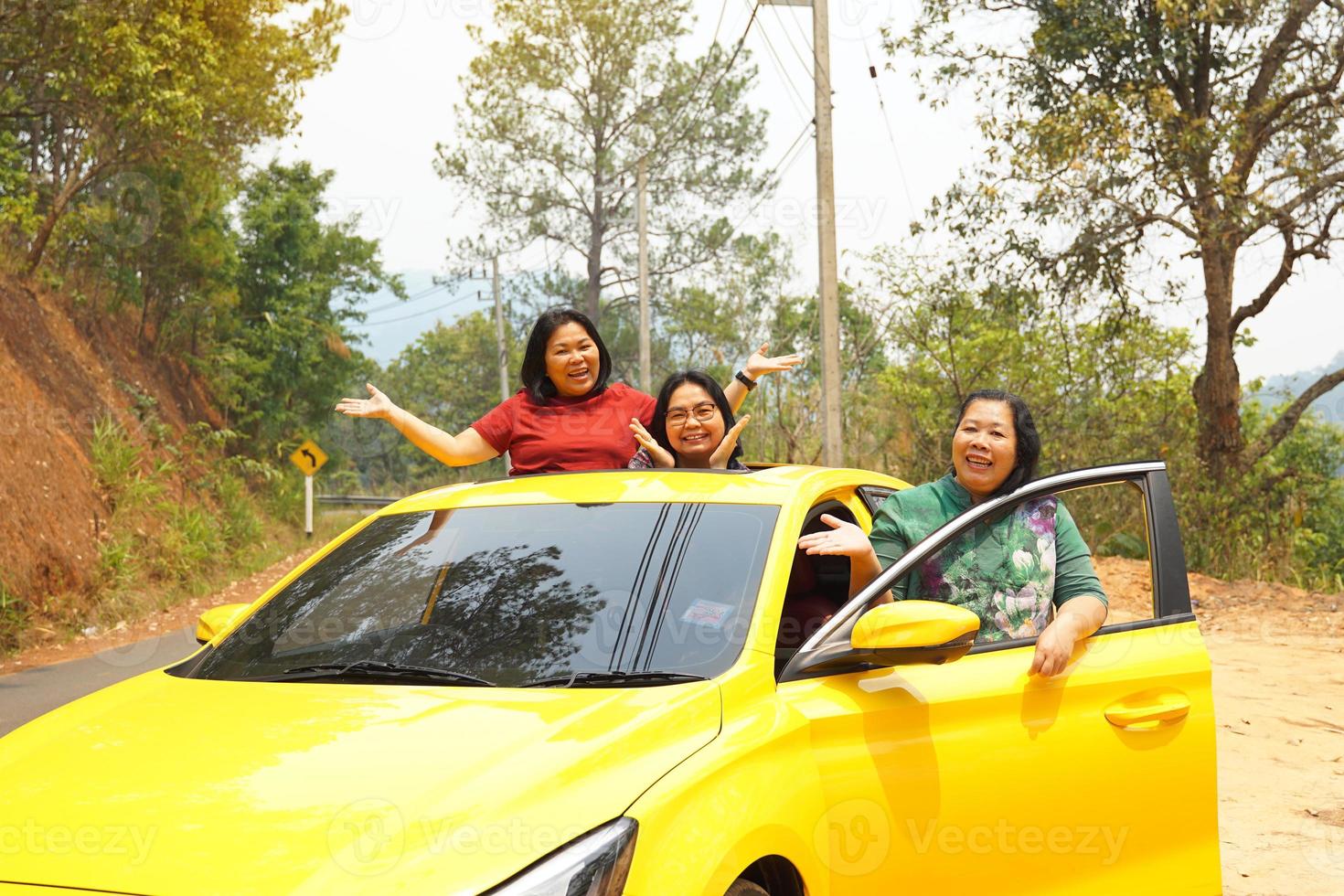 de edad mediana asiático mujer y amigos con un del amante amarillo sedán. todos sonrió felizmente. a viaje el montañas en un verano vacaciones juntos.suave y selectivo enfocar. foto