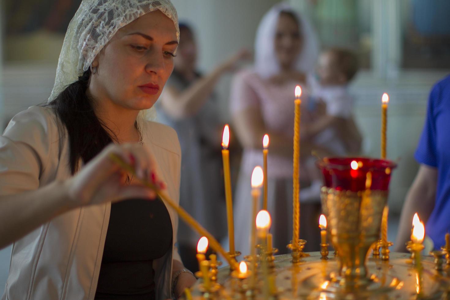 Women lights a church candle. photo