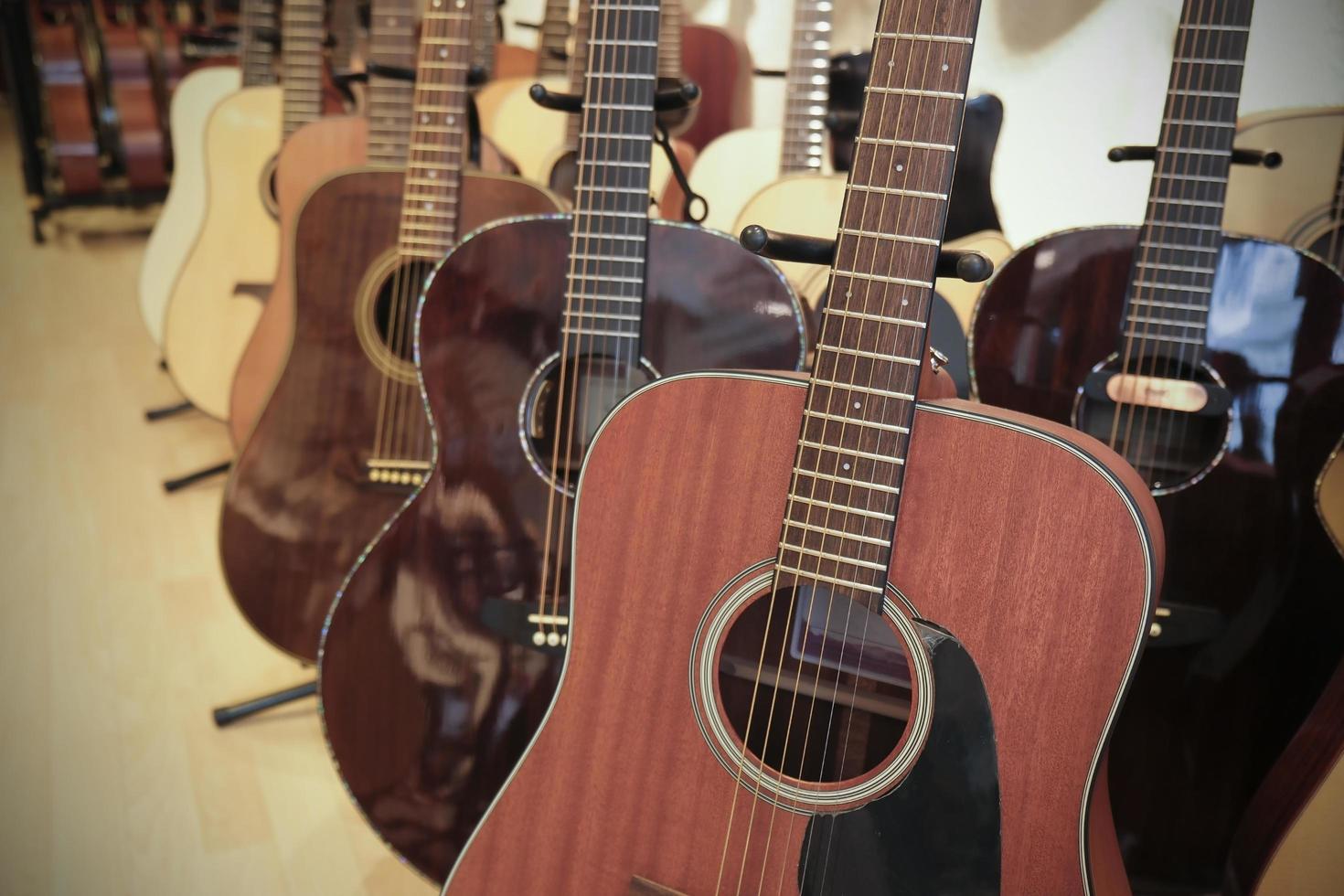 Many acoustic guitars are in a store photo