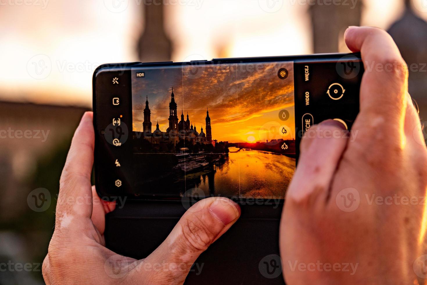 picturesque sunset on a summer day in the city of Zaragoza in Spain with a view of the river and the cathedral while taking a photo with a mobile phone