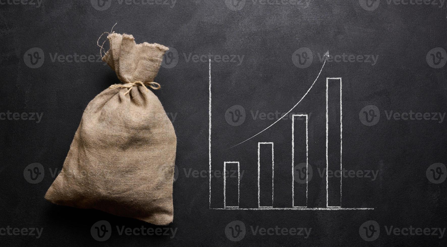 A full canvas bag and a graph drawn in chalk on a black board. Growth of incomes, receipt of subsidies, increase in income photo