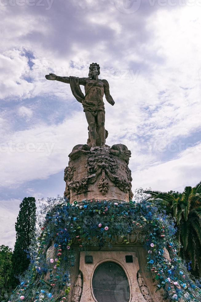 neptune fountain statue in a park in saragossa spain decorated with flowers photo