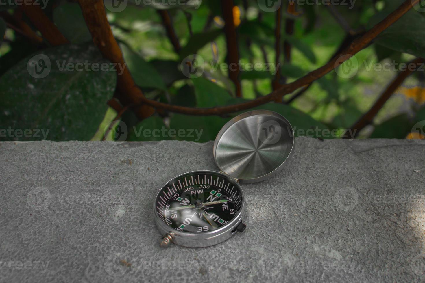 Concept for nature and adventure. After some edits, a photo of a compass placed outdoor near a tree.
