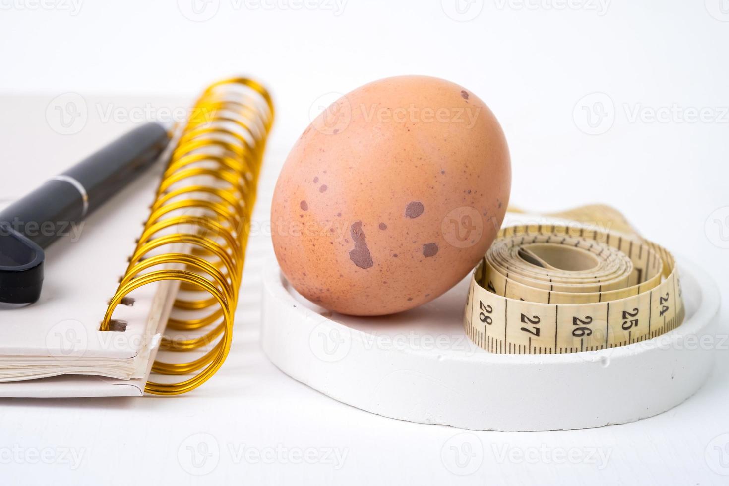 pollo huevo y medición cinta y bolígrafo en blanco antecedentes. dieta concepto foto