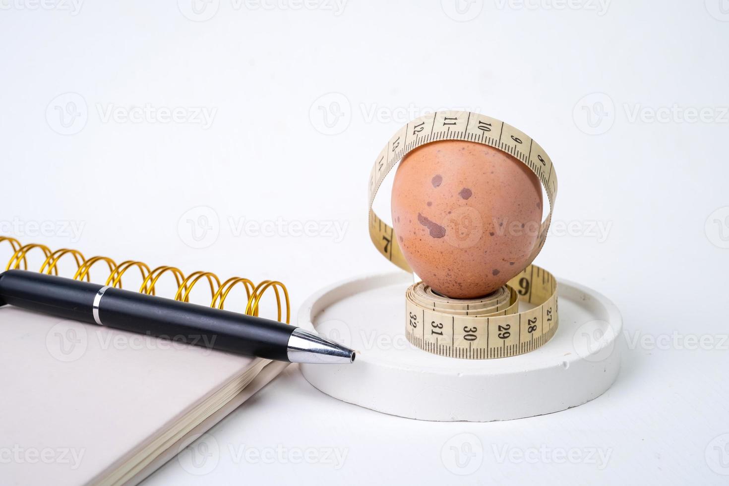 Chicken egg and measuring tape and pen on white background. Dieting concept photo