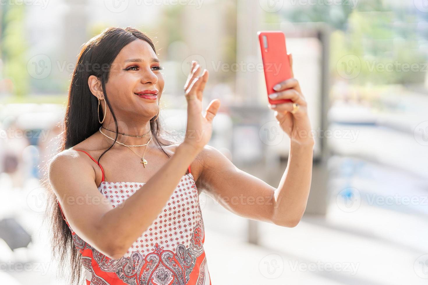Trans woman waving at the mobile while doing video call photo