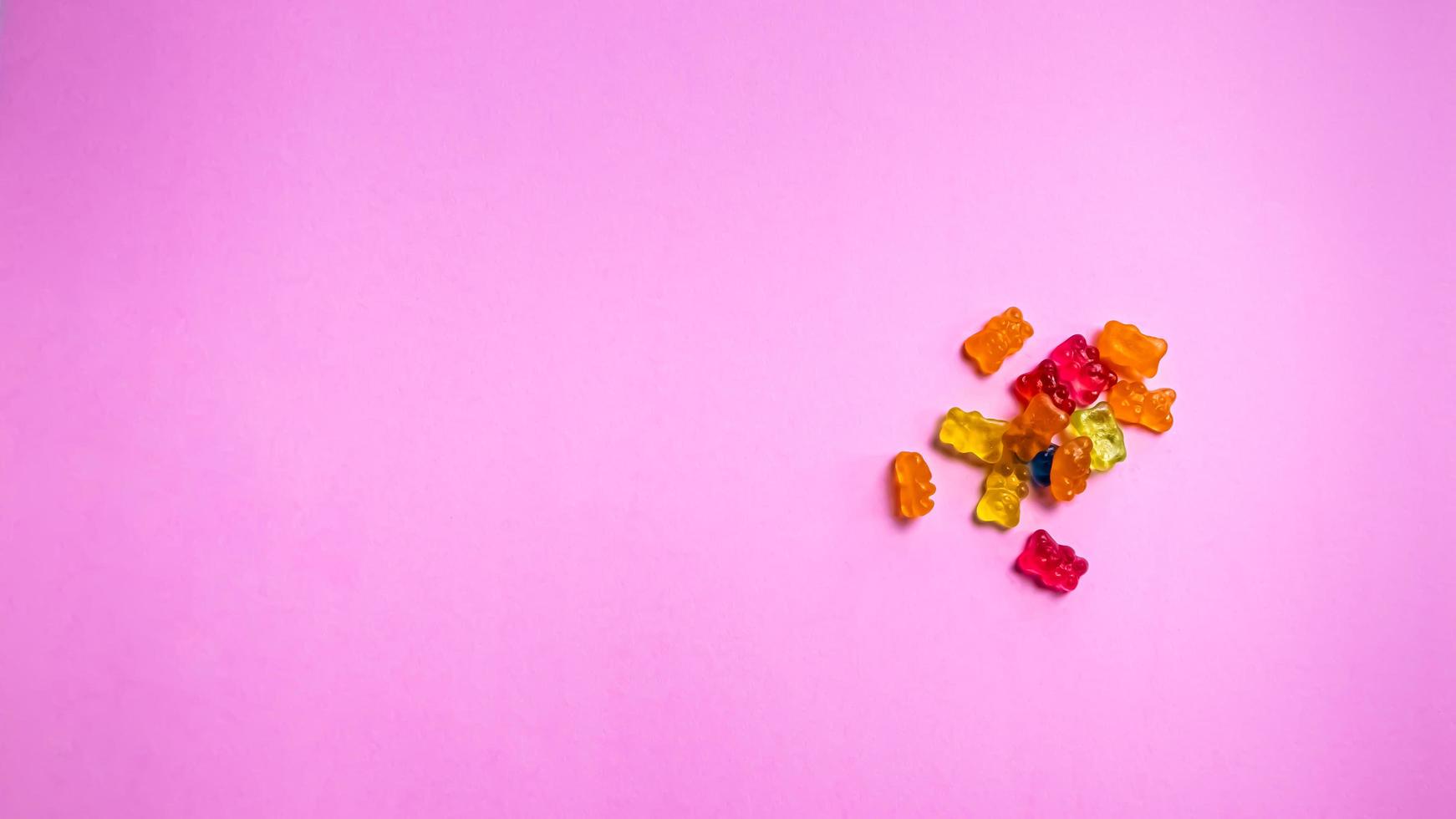 Colorful gummy bear candies on pink background. Top view. photo