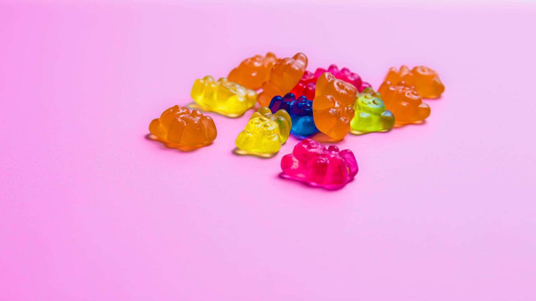 Colorful gummy bear candies on pink background. Top view. photo