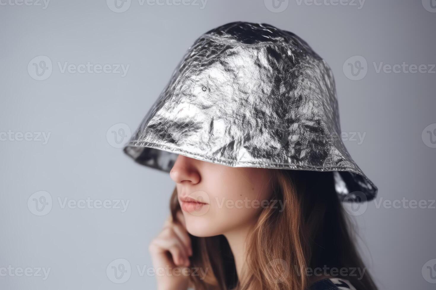 A person wears a small handmade hat made of aluminium foil on a light background to protect himself from radiation and conspiracy theory created with technology. photo