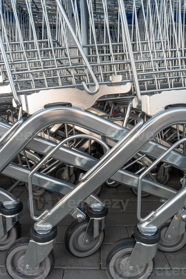 Empty stainless steel modern shopping carts standing at the supermarket in a row in line unused. photo