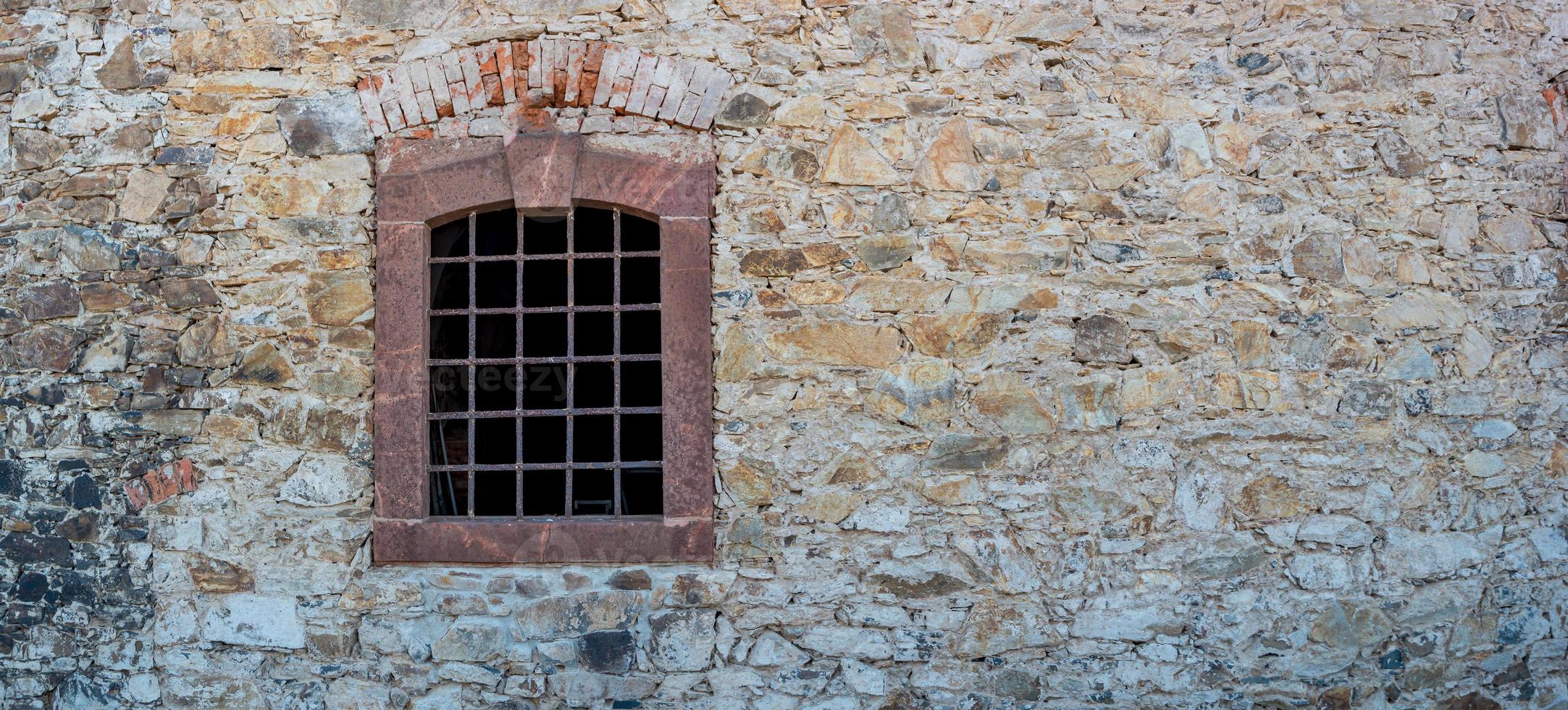 Banner with ancient stone wall and a metal grid window as a prison with copy space background. Concept of freedom and liberty. photo