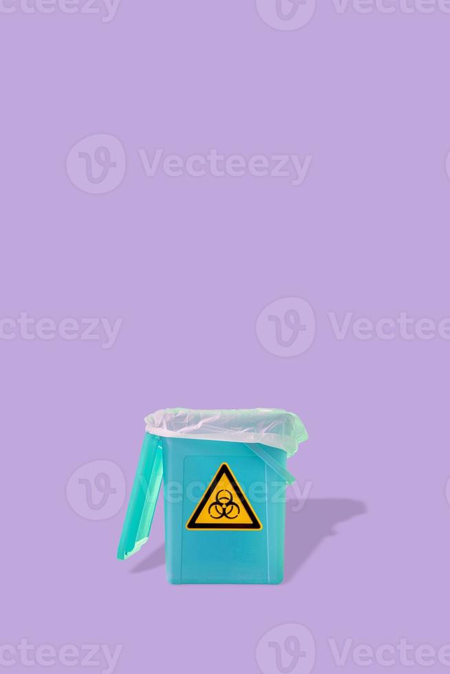 Fluorescent garbage trash bin with its shadows and radiation damger orange symbol isolated at purple solid background. Concept of nuclear waste recycling and environment. photo