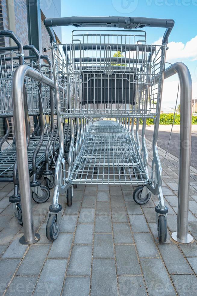 Empty stainless steel modern shopping carts standing at the supermarket in a row in line unused. photo