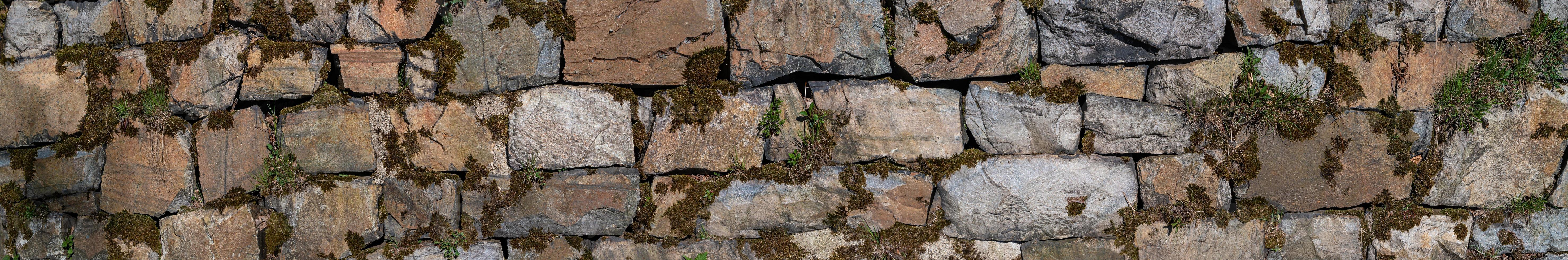 Panoramic view over a long middle age stone wall with patterns of ancient bricks and stones as a background, closeup, details. photo