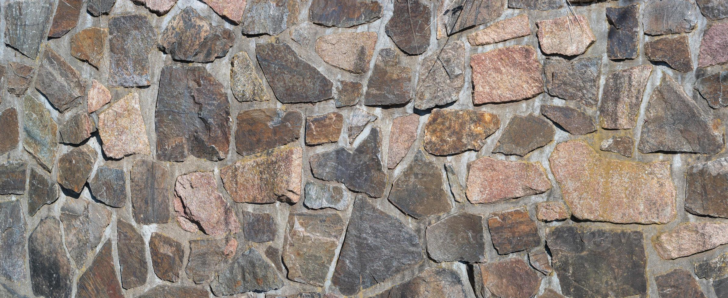 Panoramic view over a long middle age stone wall with patterns of ancient bricks and stones as a background, closeup, details. photo