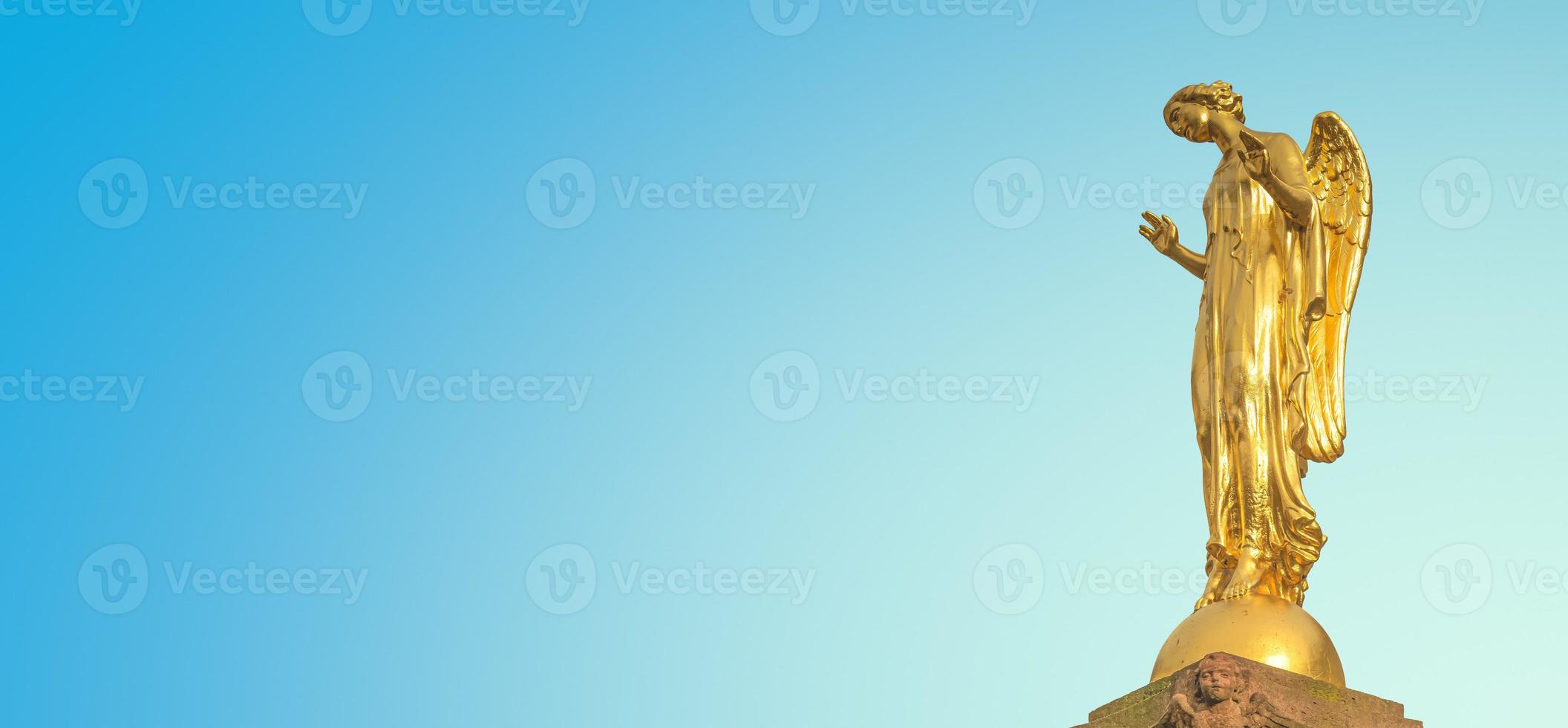 Banner with a beautiful golden angel column statue at Market Square in small town Mittweida, its historical downtown, Saxony, Germany, at blue sunset sky solid background with copy space. photo