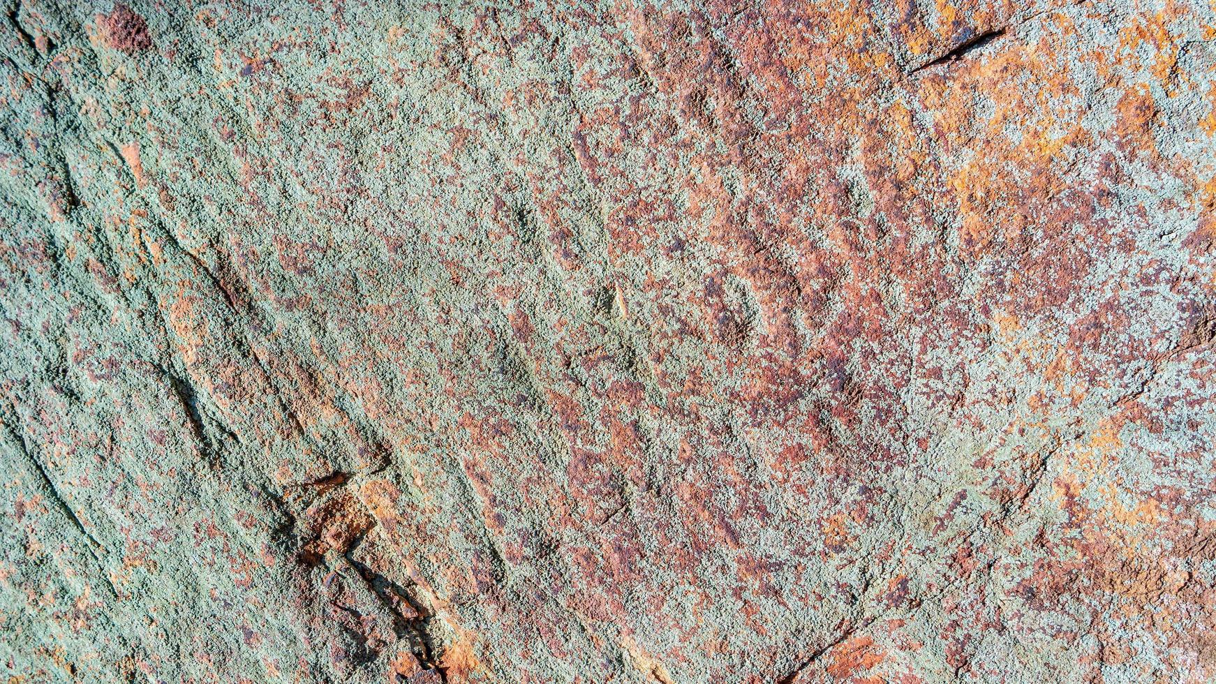 Pattern of granite stone wall covered with moss and lichen, as a background, closeup, details. photo