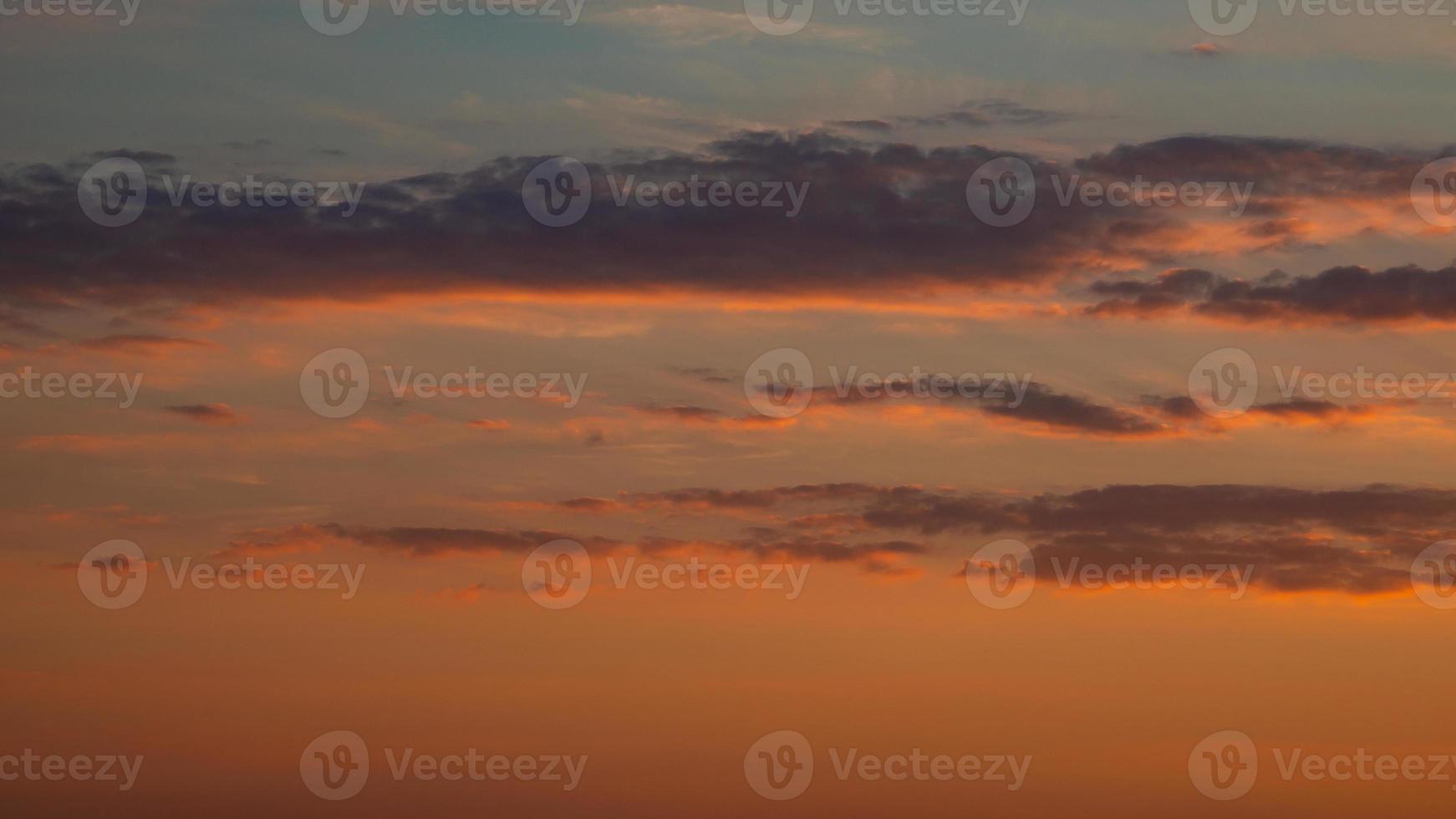 suave profundo naranja cielo, iluminado nubes a sangriento puesta de sol como un antecedentes. foto