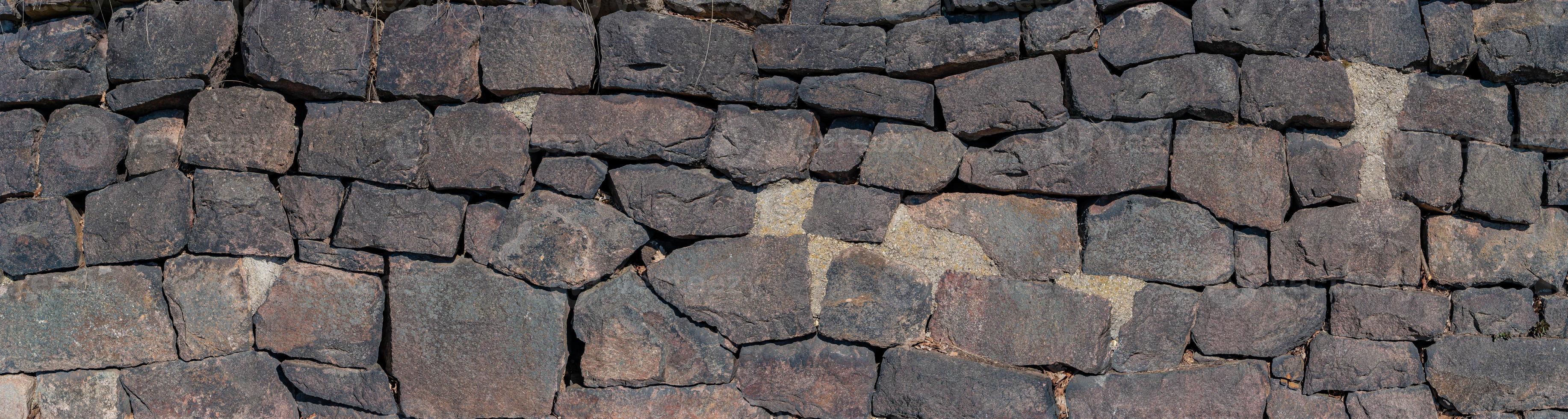 Panoramic view over a long middle age stone wall with patterns of ancient bricks and stones as a background, closeup, details. photo