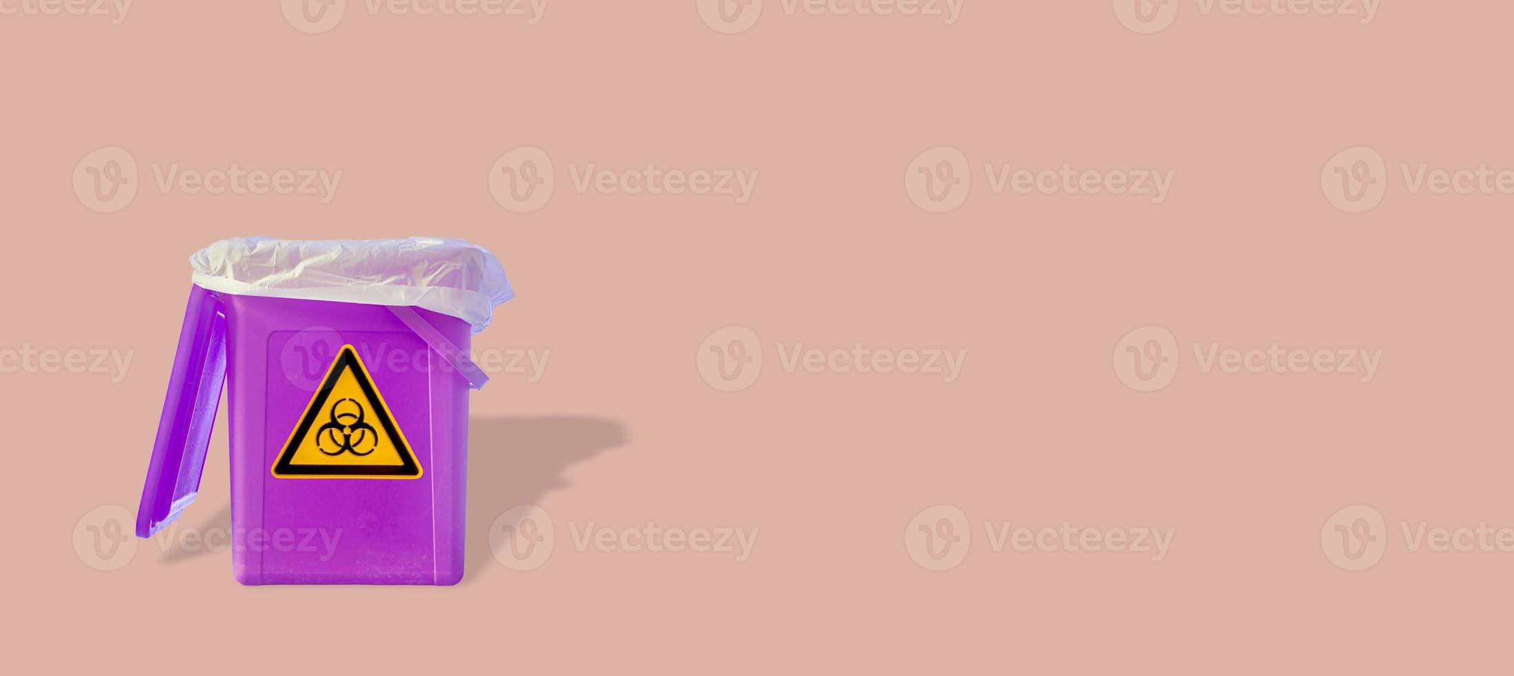 Fluorescent garbage trash bin with its shadows and radiation danger orange symbol isolated at pink solid background. Concept of nuclear waste recycling and environment. photo