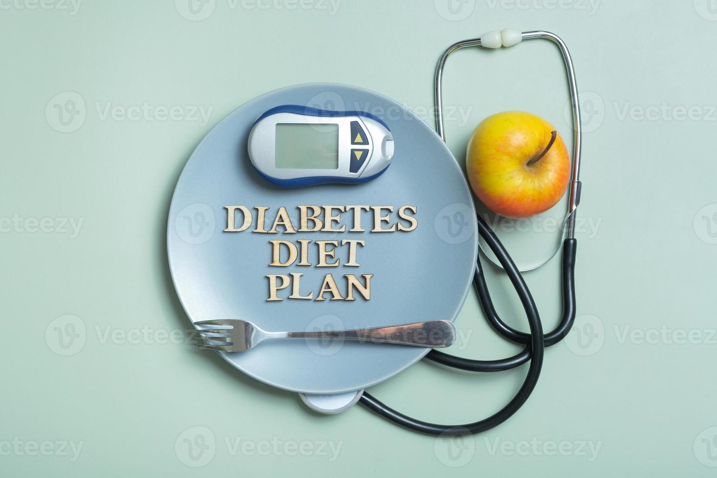 Diabetes Diet Plan text. Stethoscope, glucometer and plate on colored background flat lay, top view photo