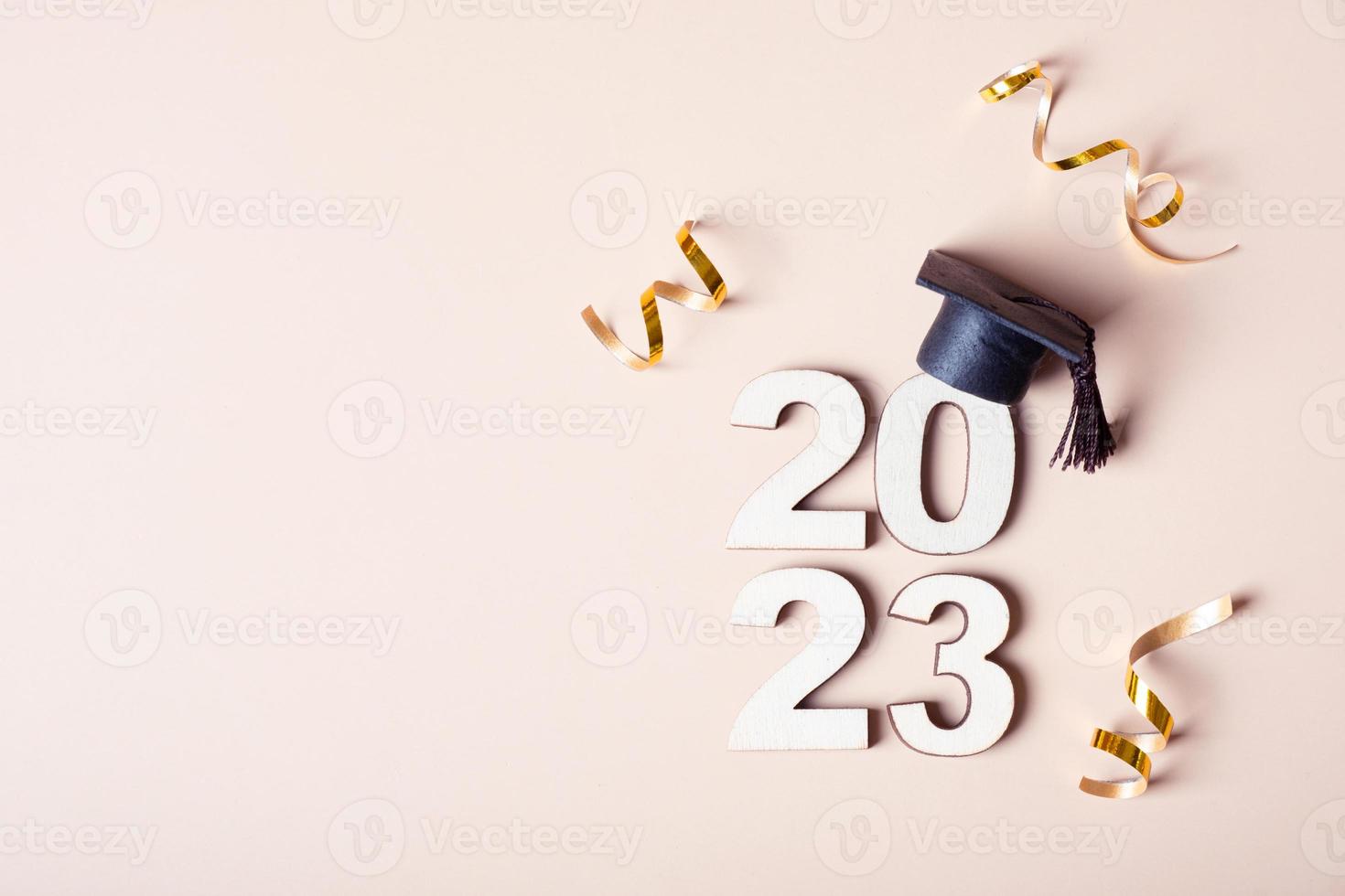 Class of 2023 concept. Wooden number 2023 with graduated cap on colored background photo