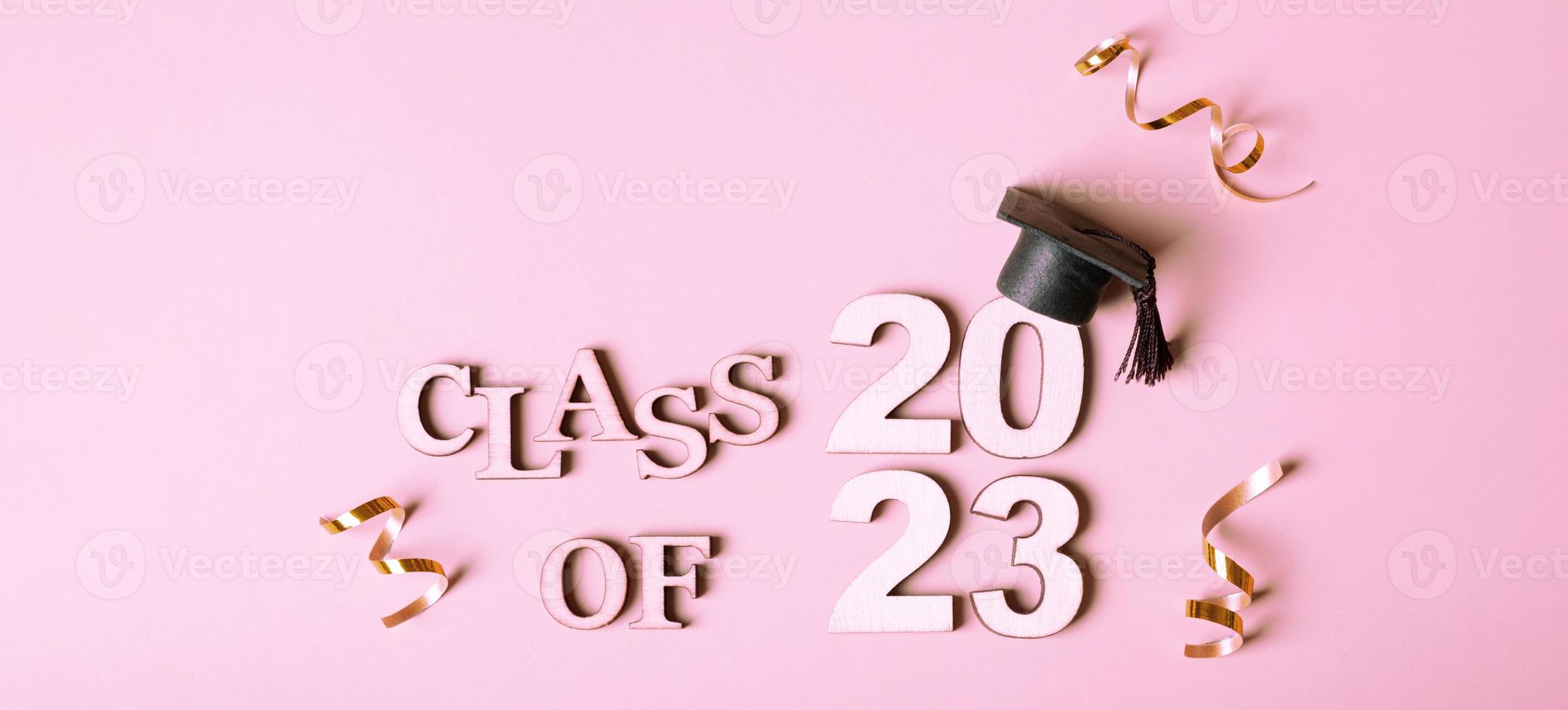 Class of 2023 concept. Wooden number 2023 with graduated cap on pink background photo