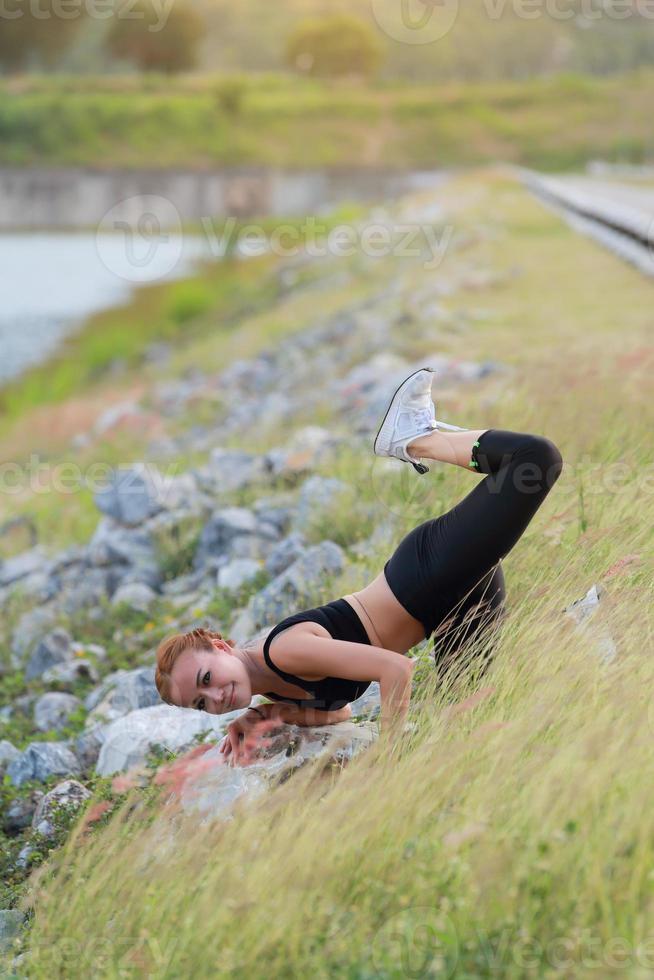 joven niña haciendo yoga aptitud ejercicio Mañana amanecer al aire libre en el prado hermosa montañas paisaje. meditación y relajarse. foto