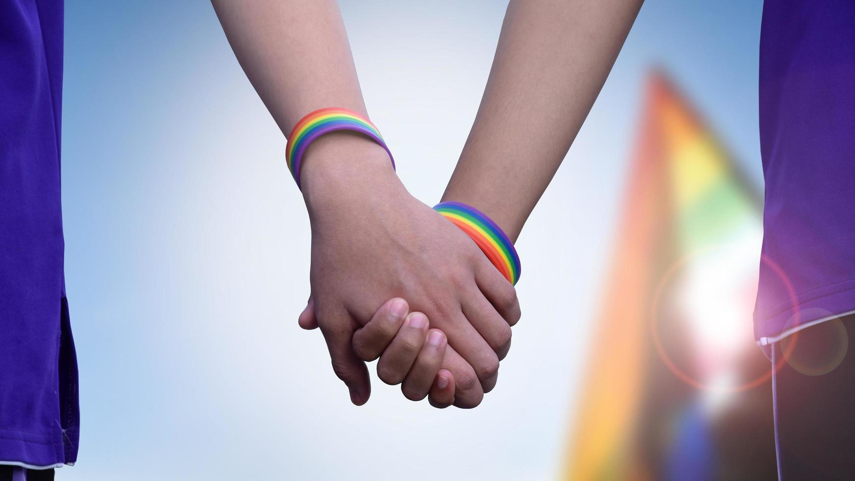 humano manos cuales vestir arco iris pulsera alrededor a ellos, concepto para lgbt personas celebracion en orgullo mes, junio, alrededor el mundo. foto