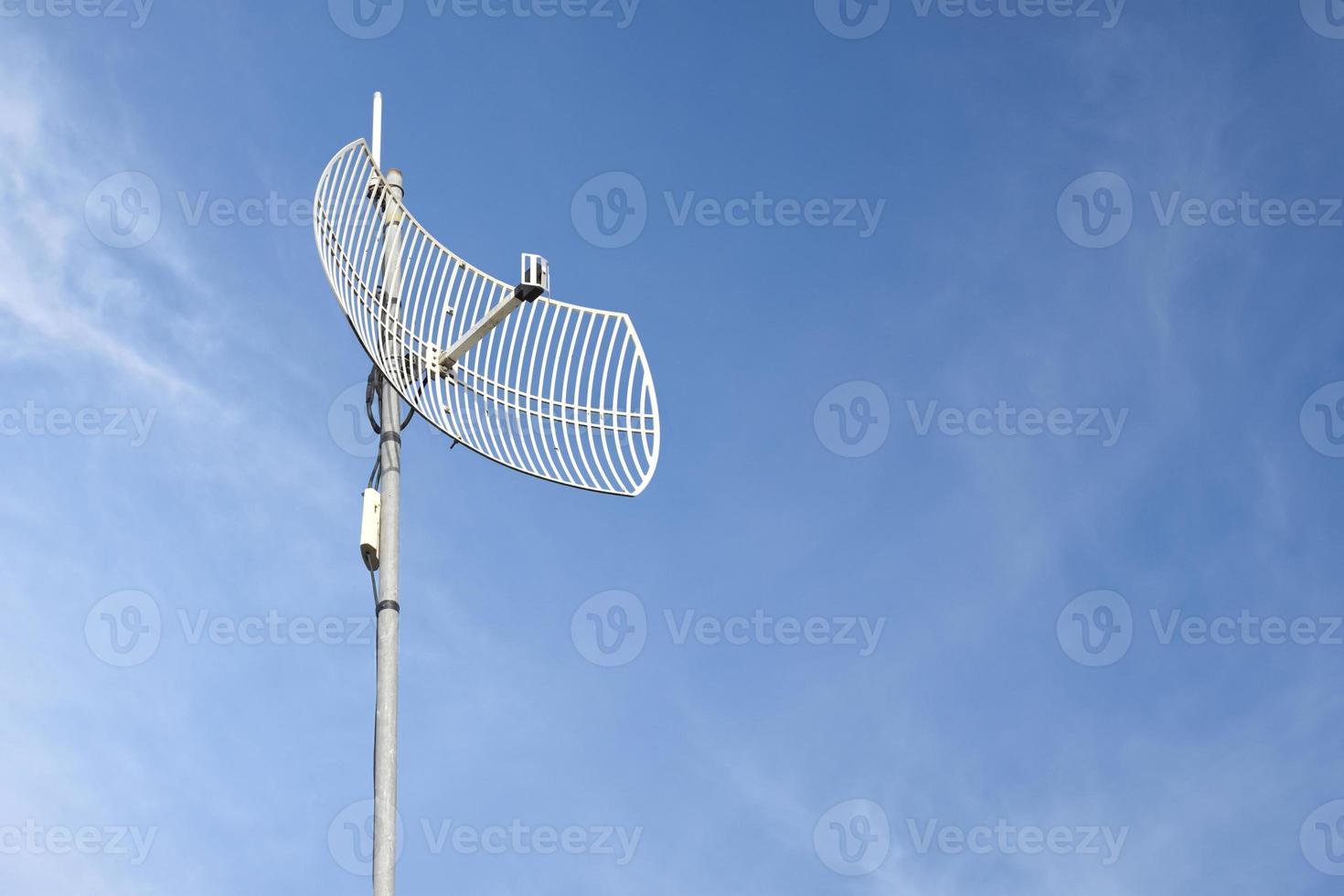 Internet wireless wifi receiver and repeater installed on metal pole on the roof of the building to service internet to users in local village, soft and selective focus. photo