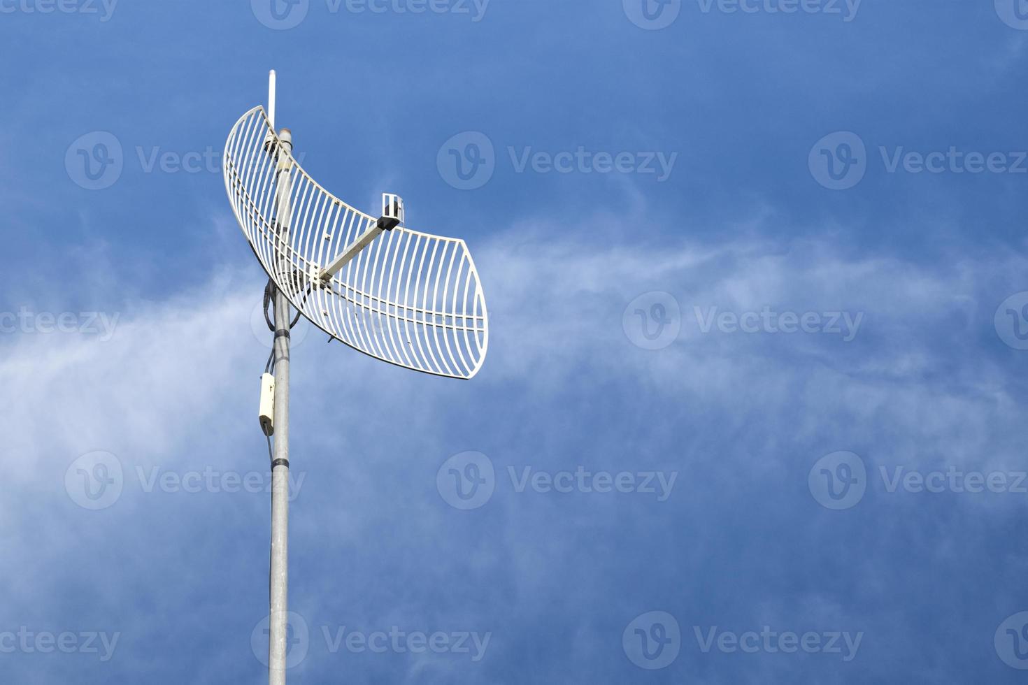 Internet wireless wifi receiver and repeater installed on metal pole on the roof of the building to service internet to users in local village, soft and selective focus. photo