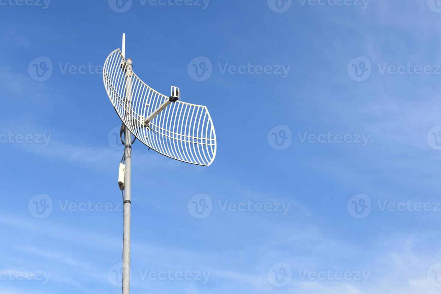 Internet wireless wifi receiver and repeater installed on metal pole on the roof of the building to service internet to users in local village, soft and selective focus. photo