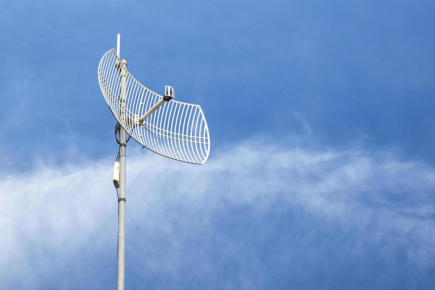 Internet wireless wifi receiver and repeater installed on metal pole on the roof of the building to service internet to users in local village, soft and selective focus. photo