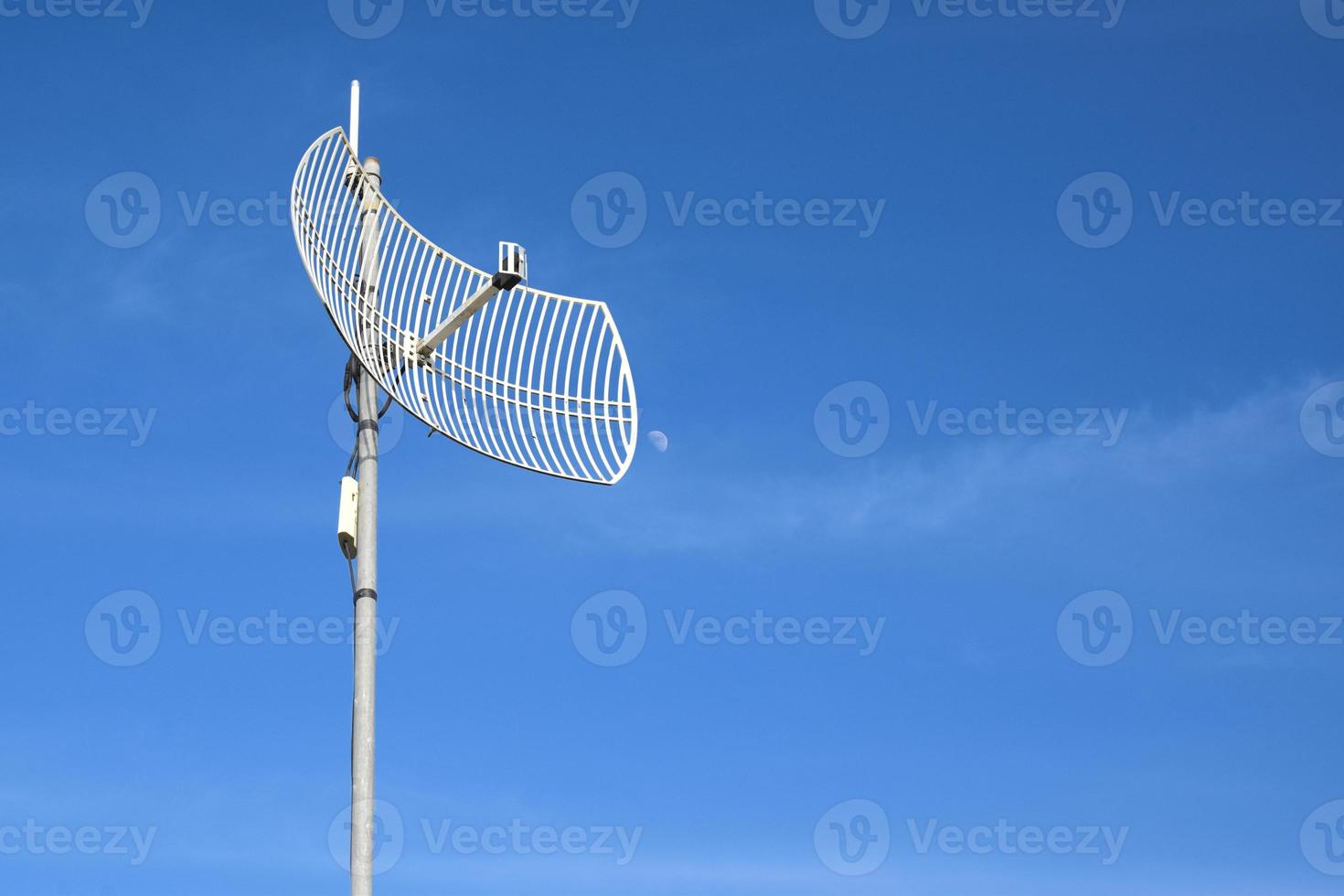 Internet wireless wifi receiver and repeater installed on metal pole on the roof of the building to service internet to users in local village, soft and selective focus. photo