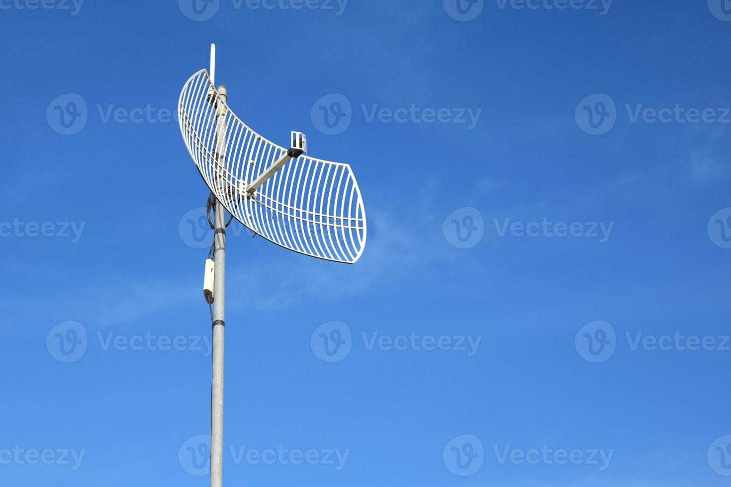 Internet wireless wifi receiver and repeater installed on metal pole on the roof of the building to service internet to users in local village, soft and selective focus. photo