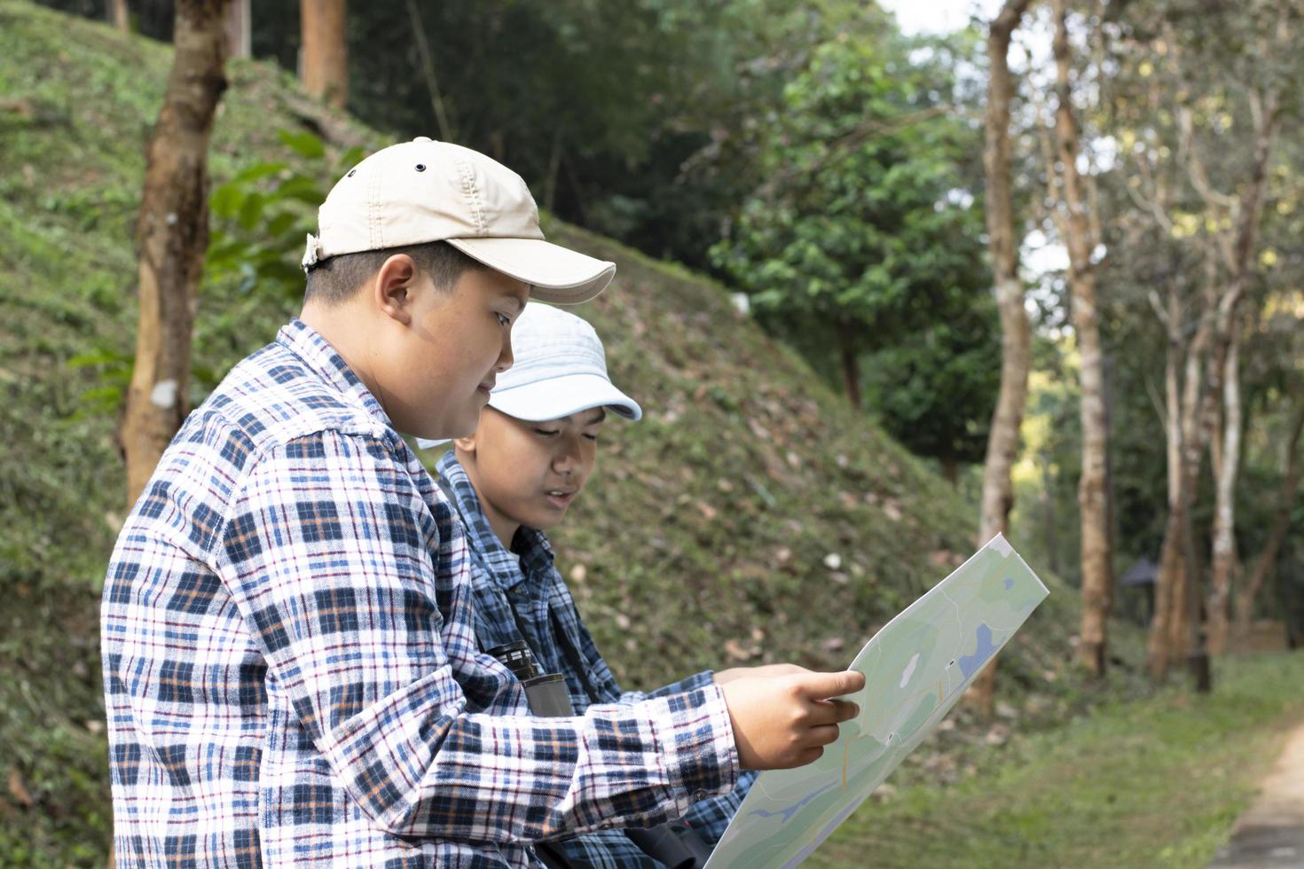 Asian boys using binoculars to do the birdwatching in tropical forest during summer camp, idea for learning creatures, wildlife animals and insects outside the classroom. photo
