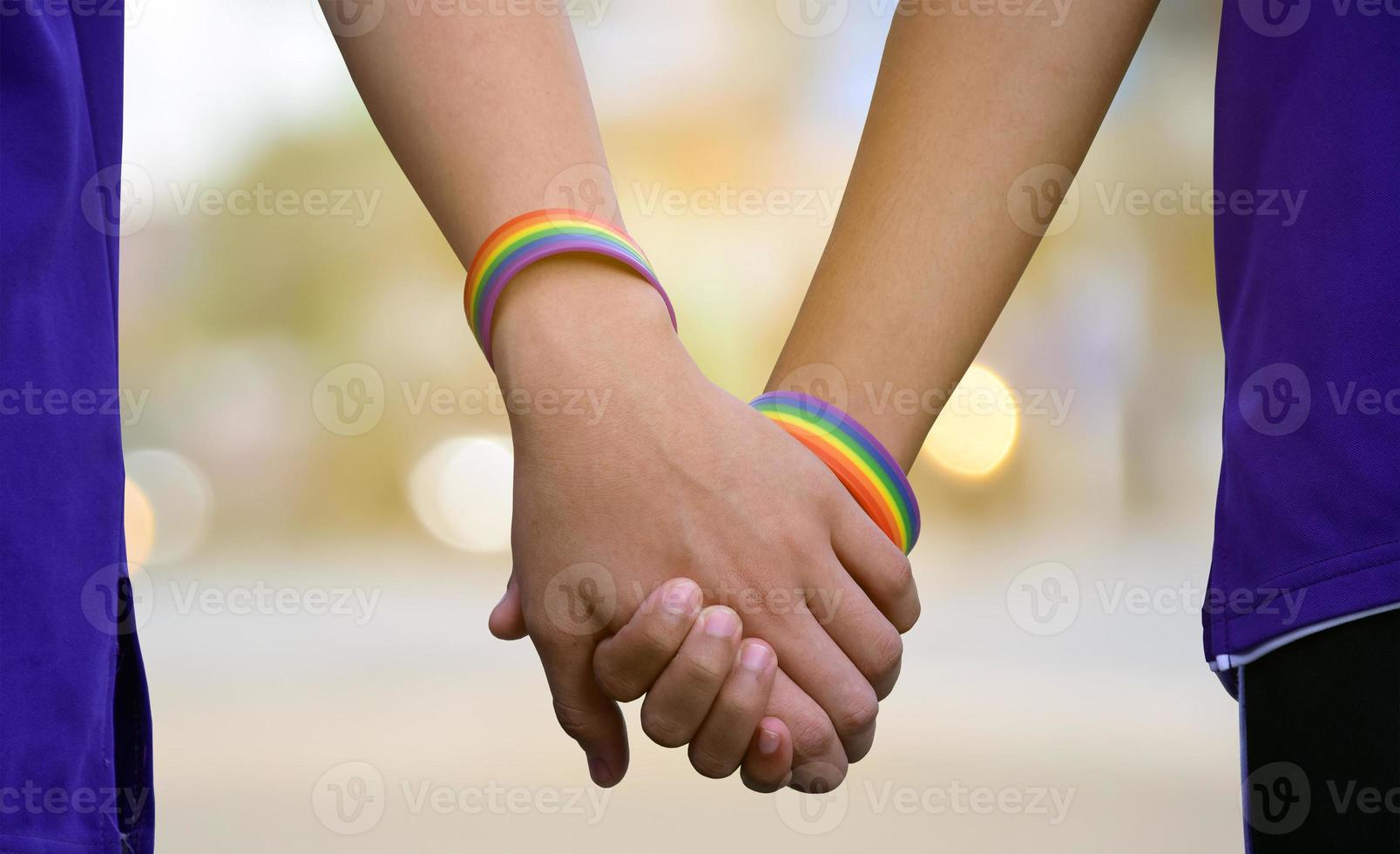 Closeup hands which wear rainbow wristband around them of gay couple, concept for LGBT people presenting their love to all gender people around the world. photo