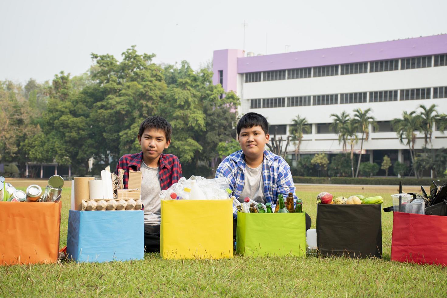 asiático Niños son separando basuras y poniendo ellos dentro el cajas en frente de ellos cerca edificio, suave y selectivo enfocar, ambiente cuidado, comunidad Servicio y verano vacaciones ocupaciones concepto. foto