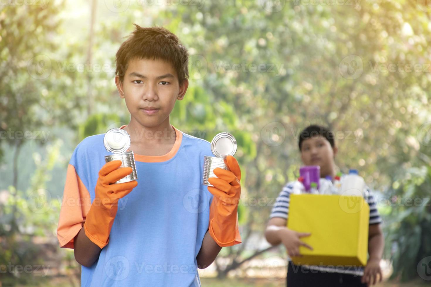 Young asian boy sorting various garbages and putting them into the boxes infront of him in the park, nature care and environment love concept. photo